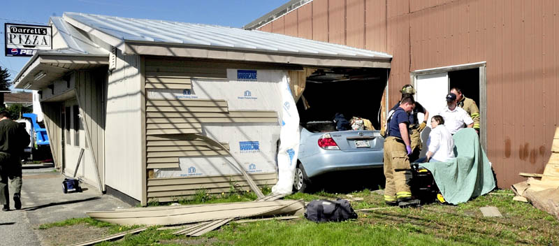 CRASH: Driver Sharon Roderick of Fairfield is treated on a gurney after being removed from her vehicle that crashed through a wall and into the Darrell's Pizza building in Waterville on Monday.