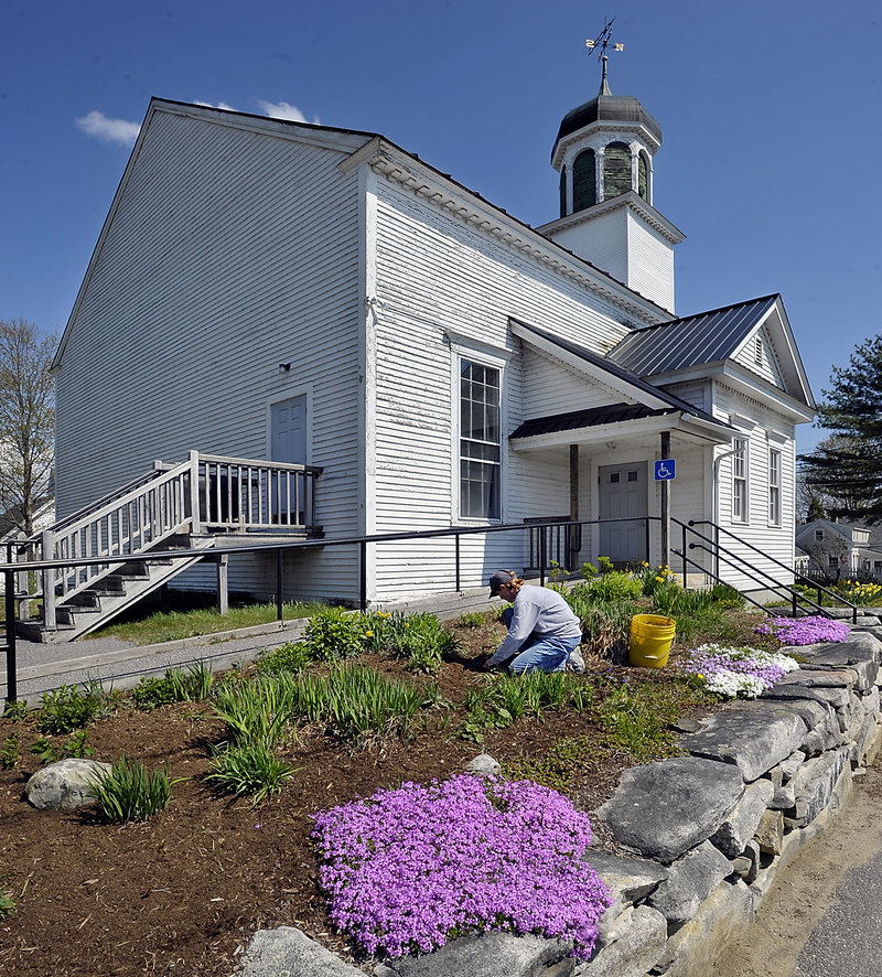 Sam Stetson of Bowdoinham cleans the garden around the original Town Hall, which hosts the annual plant sale.