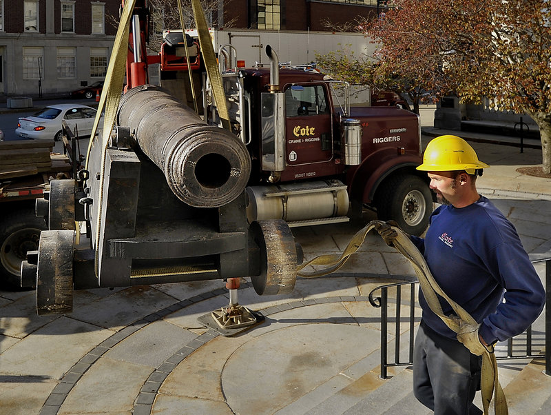 Steve Bosse, an employee of Cote Crane and Rigging, guides the historic cannon as a crane moves it from the steps of Portland City Hall to a truck for transport to the Maine Maritime Museum in Bath for the bicentennial exhibit of the War of 1812.