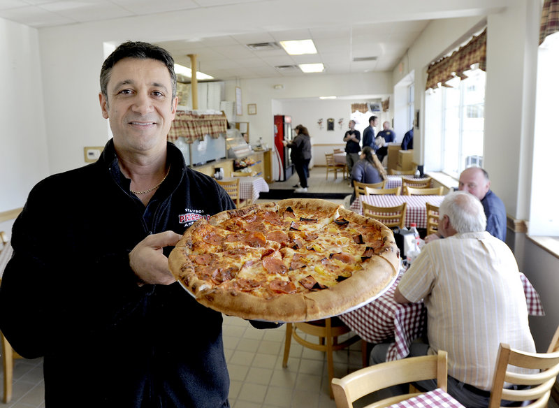 Steve Kombakis, owner of Stavros Pizzeria and Deli in Portland, shows off a half-pepperoni, half-Hawaiian pizza.