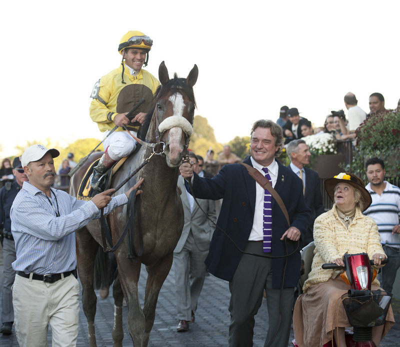 Jamie Wyeth, wearing the purple tie, leads Union Rags down victory lane at Belmont Park after the Champagne Stakes in October 2011. At right is his wife and the horse’s owner, Phyllis, operator of Chadds Ford Stable in Pennsylvania.