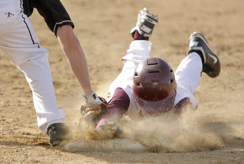 Connor Maguire of Cape Elizabeth gets a face full of dirt as he dives back to first ahead of the tag by Greely’s Luke Saffian in Monday’s game at Cumberland. Greely won, 8-0.