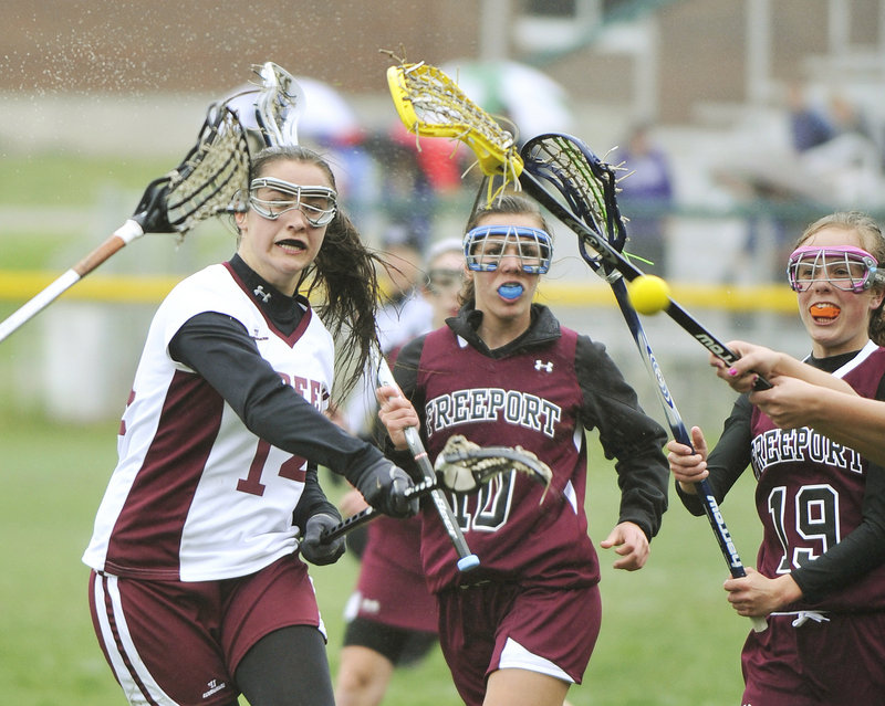 Paige Tuller of Greely takes a shot while being pursued by Freeport’s Bethanie Knighton, center, and Emily Johnson during a lacrosse game Tuesday in Cumberland. Tuller scored on the shot, but Freeport rallied for a 12-11 victory.
