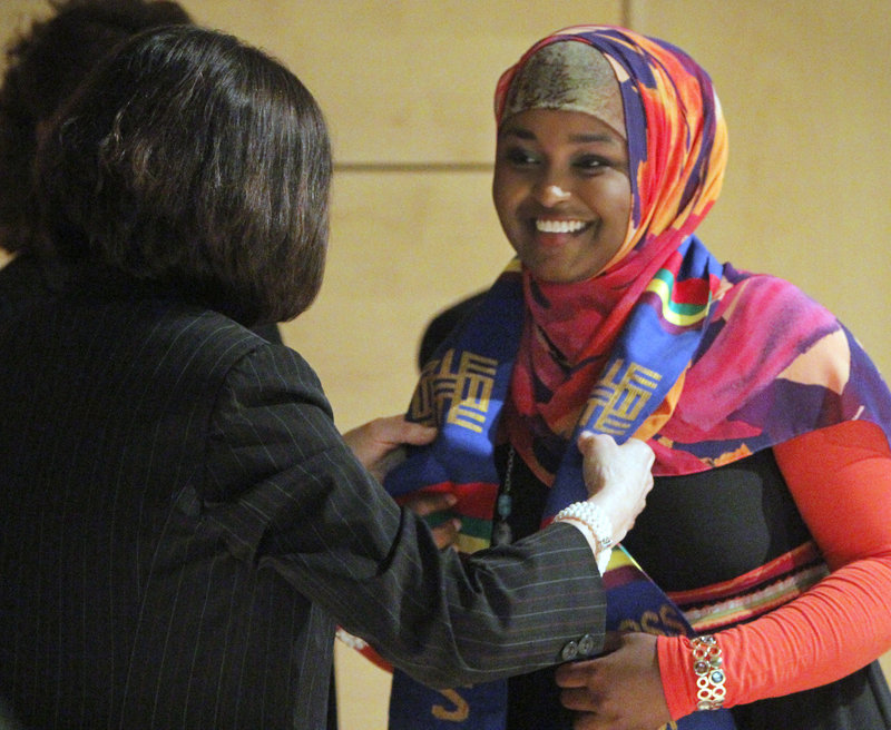 Faiza Ahmed receives a graduation sash from USM President Selma Botman.