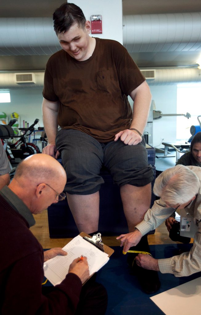 Igor Vovkovinskiy of Rochester, Minn., the tallest man in the United States, has his feet measured by shoe technicians as part of a shoe fitting at Reebok headquarters in Canton, Mass., Thursday.