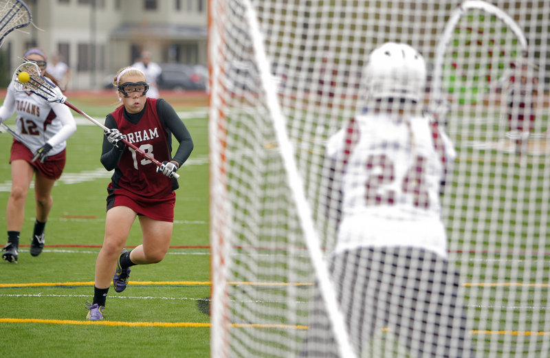 Meghan Cushing of Gorham advances against Thornton Academy goalie Alexandria McCarthy to score the goal that made it 9-9. Gorham went on to an 11-10 victory in a schoolgirl lacrosse game Thursday.