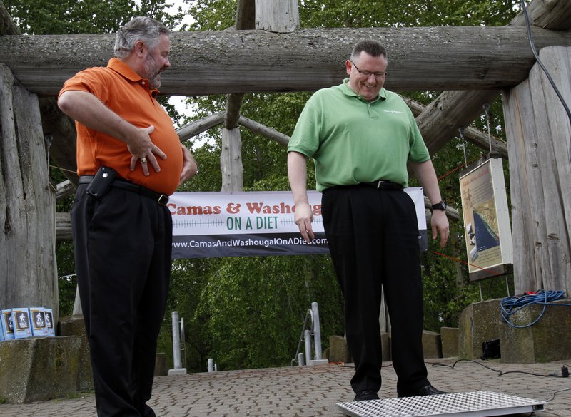Washougal, Wash., Mayor Sean Guard, left, coaxes Camas Mayor Scott Higgins to step on the scales during a weigh-in this month. The mayors of the two neighboring towns are in a “Biggest Loser”-style contest to see which of the two communities can lose the most weight.
