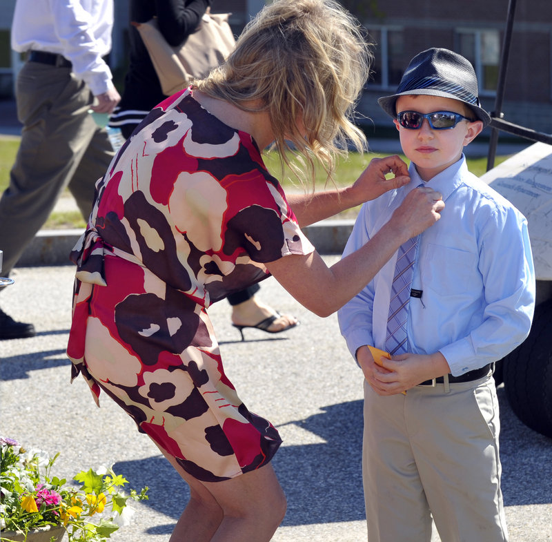 Katie Garske adjusts the tie of Brady Egan, 8, from Seattle, prior to the start of the Saint Joseph’s College ceremonies. They were attending the event for T.J. Garske of Federal Way, Wash., who was getting a bachelor's of science.