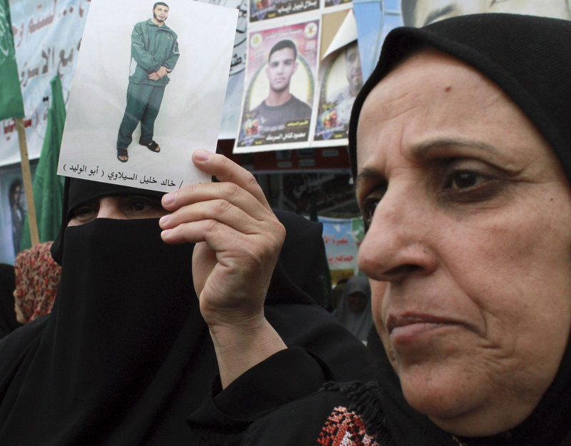 Palestinian women, one holding a photograph of a prisoner, participate in a solidarity protest with Palestinian prisoners jailed by Israel, in Gaza City on Monday.
