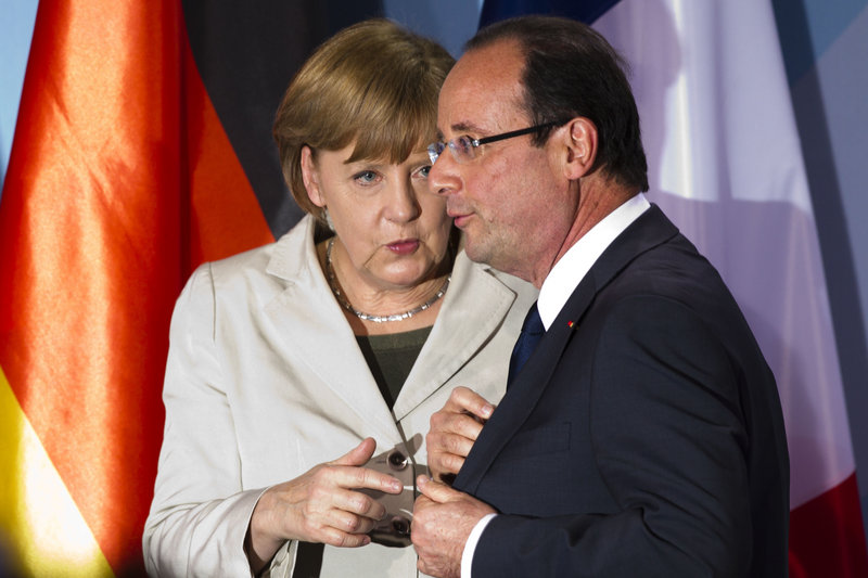 German Chancellor Angela Merkel talks to French President Francois Hollande after a news conference Tuesday in Berlin. They met for the first time since Hollande took office.