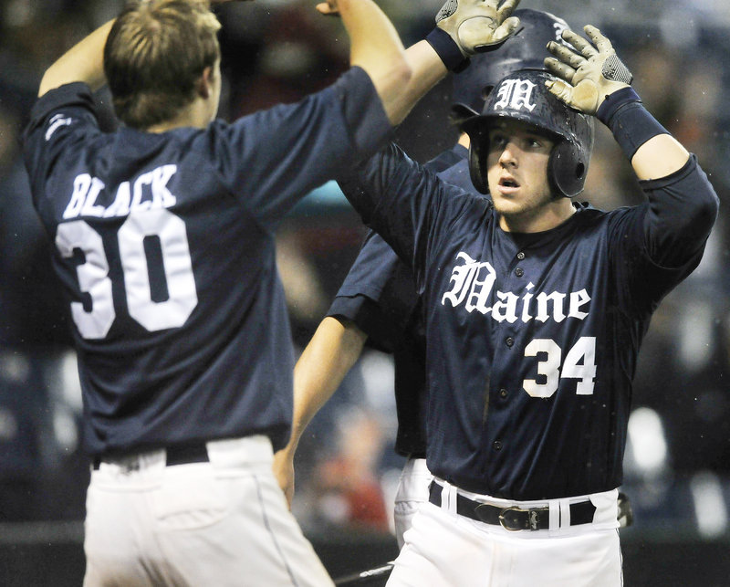 Tyler Patzalek of the University of Maine, right, is greeted by teammate Troy Black after scoring during a four-run seventh inning in a 9-4 victory over Boston College.