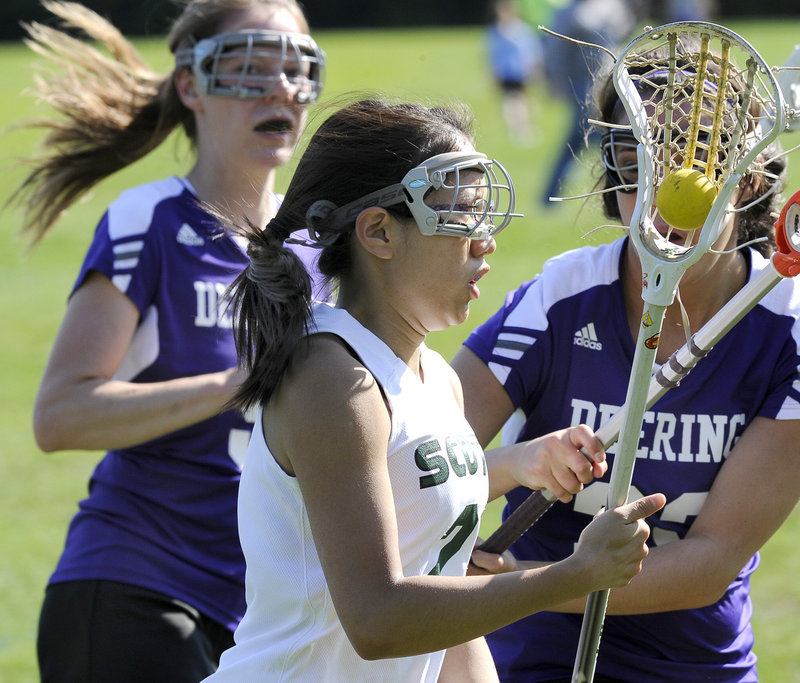 Leah Carter of Bonny Eagle advances the ball while pursued by Veronica Mitchell, left, and Casey Girsch of Deering.