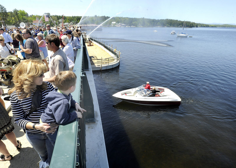 Julie Carlson of Naples holds her grandson, 3-year-old Jaiden Meehan, as they wait for state and local officials to celebrate the opening of the bridge between Long Lake and Brandy Pond on Friday. The entire project could be finished by this fall.