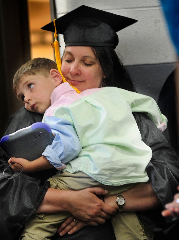 Ali Maguire of Kennebunk shares a quiet moment with her son Duncan Blanchard, 4, before marching out to receive her degree in paramedicine.