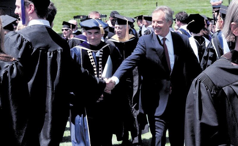 Former British Prime Minister Tony Blair shakes hands with a Colby College graduate after commencement Sunday. College President William Adams is left of Blair.