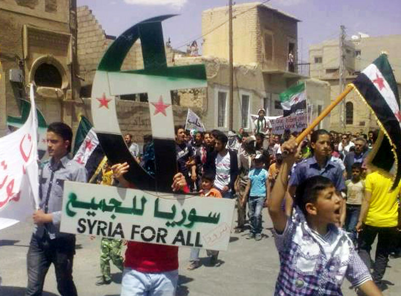 In this citizen journalism image, a protester against the regime of Syrian President Bashar Assad holds up a Cross and Crescent painted the colors of the Syrian revolutionary flag during a protest Friday in Yabroud, Syria. On Sunday, an anti-Assad cleric and his bodyguard were killed in Lebanon.