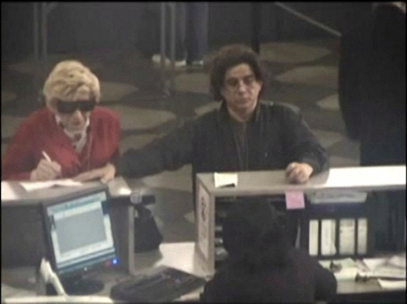 Prosecutors say this 2009 photo shows Thomas Parkin, left, on a Department of Motor Vehicles security camera, dressed as his late mother in order to collect her benefits. At right is Mhilton Rimolo, who authorities say was an accomplice.