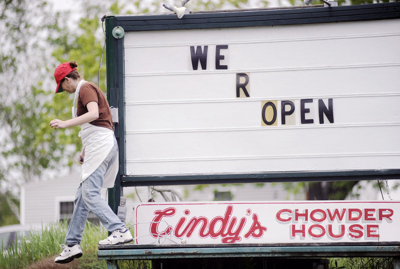 Lena Gage of Cindy’s Chowder House in Freeport modifies the sign at her business on Thursday, in preparation for the tourist season that starts in earnest this holiday weekend.