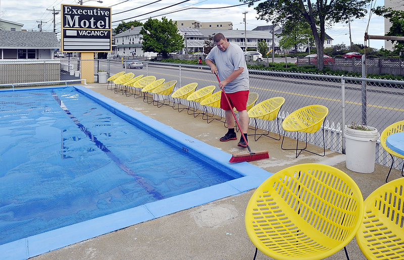 Karl Finley sweeps the area around the pool Wednesday at the Executive Motel on East Grande Avenue in Old Orchard Beach as he and other business owners get ready for the Memorial Day weekend, the traditional start of Maine’s summer tourism season.