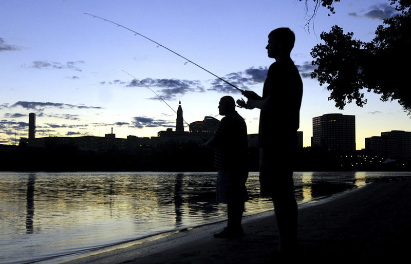 Peter Murawski, foreground, and his cousin Joe Murawski fish on the banks of the Connecticut River at Great River Park in East Hartford, as the sun sets behind the Hartford skyline. Environmental awareness led to the river’s “rebirth.”