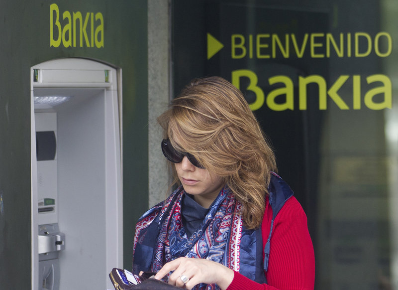 A woman uses an ATM at a branch of Bankia bank in Madrid. The bank has suffered major losses in bad loans to the real estate sector.
