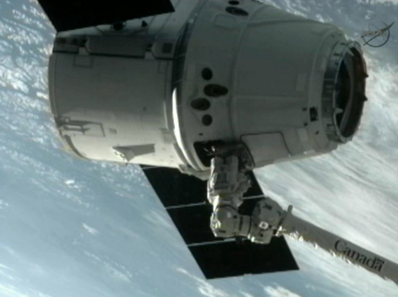 In this image provided by NASA-TV, the SpaceX Dragon commercial cargo craft is grappled by the Canadarm2 robotic arm and connected to the International Space Station on Friday.