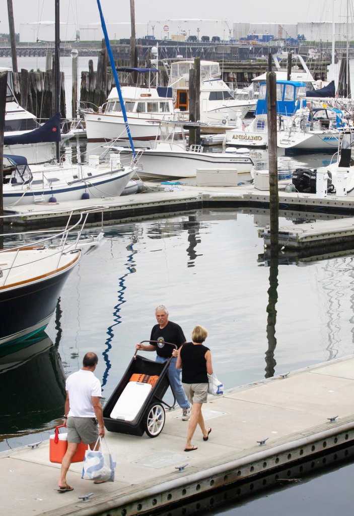 A worker passes a couple heading toward their vessel at DiMillo’s marina in Portland on Saturday, where the U.S. Coast Guard Auxiliary offered free boater safety inspections.
