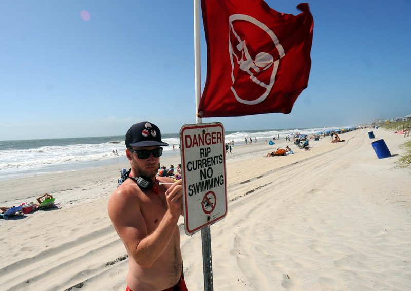 Carolina Beach Ocean Rescue squad leader Evan Anderson puts up a sign closing the beach to swimming Saturday at Carolina Beach, N.C. Tropical Storm Beryl enhanced the risk of strong rip currents.