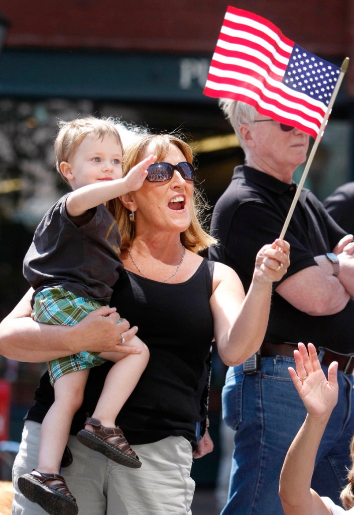 Pam Grant of Portland holds her nephew Cameron Toher, 3, also of Portland, as they enjoy the parade along Congress Street on Monday.