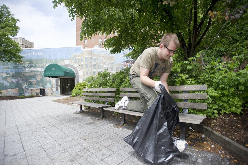 Jake Lowry gathers trash last week in Congress Square during a cleanup organized by Occupy Maine. The Eastland Park Hotel’s owners want to build a ballroom there, but Occupy Maine wants to preserve the space for public assembly.