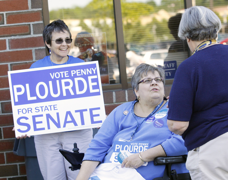 Penny Plourde, who is running for state Senate, and volunteer Donna Dachs of Augusta, left, greet people outside the Augusta Civic Center Friday.
