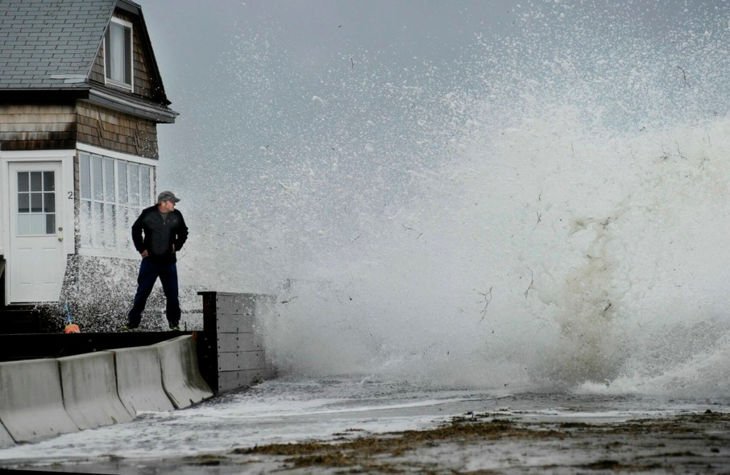 Staff Photo by Shawn Patrick Ouellette: Bernie Malouin watches a large wave crash over Eastern Ave. at Camp Ellis in Saco from a wall in front of his cottage Monday, June 4, 2012. The wave soaked Malouin who continued to monitor the high tide under the cover of his cottage after changing into some dry clothes.