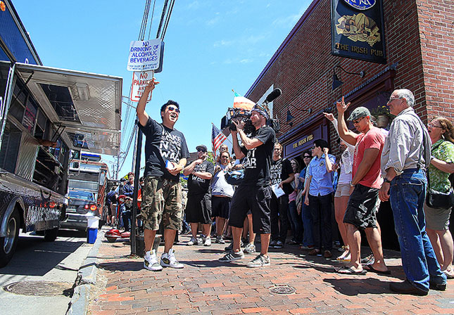 Ted Kim, center, leads the gathering crowd in a cheer just before opening the Seoul Sausage truck as The Great Food Truck Race is filmed for The Food Network in Portland outside of Ri Ra's Irish Pub on Commercial Street Sunday, June 17, 2012.