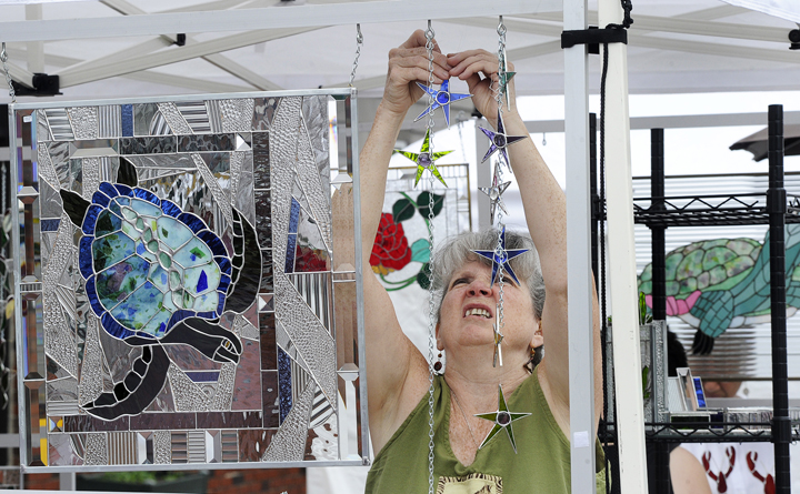 Stained-glass artist Peggy Pulling from Gorham sets up her display at the sidewalk art show today highlighting Saco's 250th Anniversary Celebration.