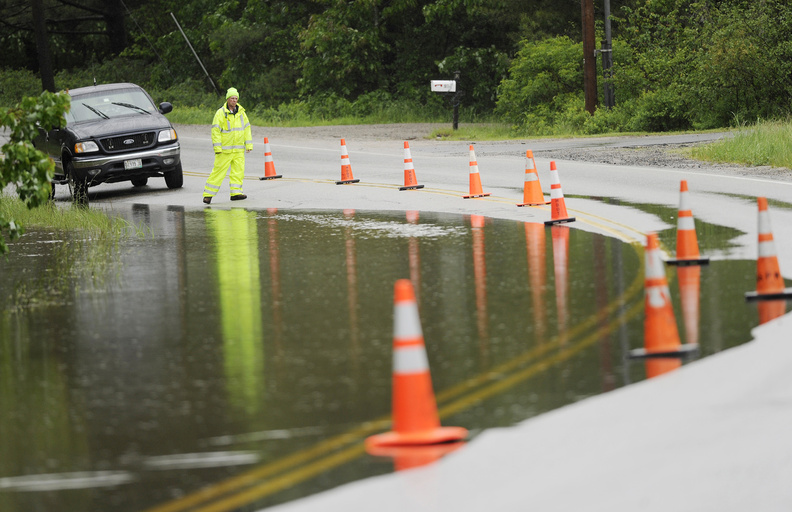 Rick Higgins, a Scarborough employee, keeps tabs on the rising water on Gorham Road in Scarborough on Sunday. Water from the nearby Nonesuch River was overtaking the road due to the heavy rain.