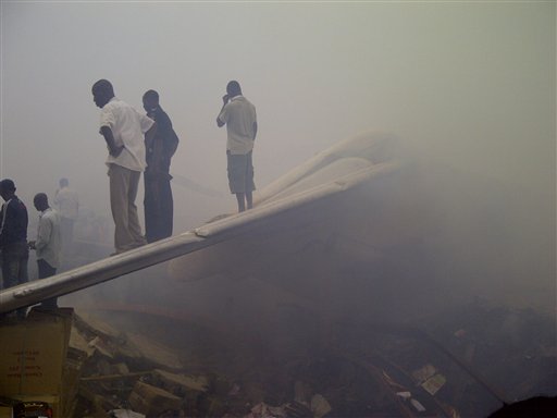 Onlookers stand on the tail wing of a crashed passenger plane in a neighborhood just north of Murtala Muhammed International Airport, in Lagos, Nigeria, today.