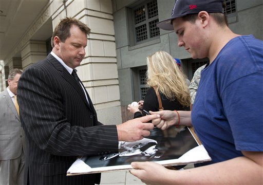 Former Major League Baseball pitcher Roger Clemens, left, signs autographs as he leave federal court in Washington on Monday.