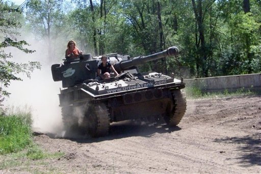 Marvin Bourne of Richmond, Va., drives a tank in Kasota, Minn., while his wife Karen Bourne looks out from the turret and Drive-A-Tank employee Kessa Baedke sits behind him.