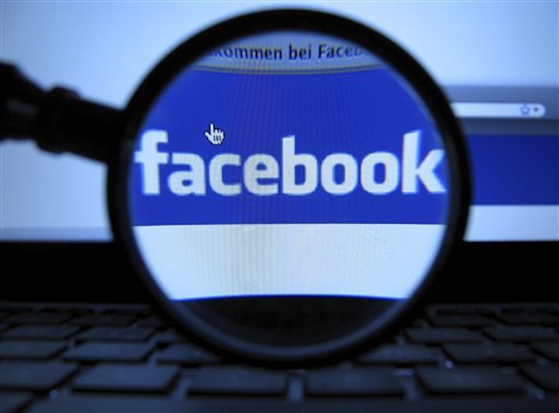 In this Oct. 10, 2011 file photo, a magnifying glass is posed over a monitor displaying a Facebook page in Munich. Facebook is paying $10 million to settle a lawsuit over ads that it called sponsored stories. (AP Photo/dapd, Joerg Koch) T2012051103645