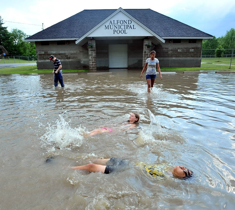 Zack Taylor, 13, foreground bottom and Caelie Burnham,12, second from bottom, float on their backs in the flood waters in the Alfond Municipal Pool on North Street in Waterville. Brandon Brown-Exner, 14, back left, and Nakia Accilien, 12, back right, walk to their friends.