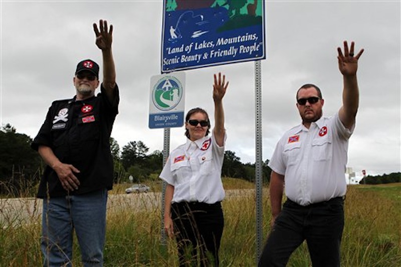 From left, Knighthawk, April Hanson and her husband Harley Hanson, members of the International Keystone Knights Realm of Georgia, perform a traditional Klan salute along the portion of highway they want to adopt allowing them to put up a sign and do litter removal near Blairsville, Ga., Sunday, June 10, 2012. The Ku Klux Klan group wants to join Georgia's "Adopt-A-Highway" program for litter removal, which could force state officials to make difficult decisions on the application. (AP Photo/The Atlanta Journal-Constitution, Curtis Compton)