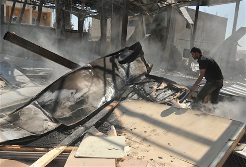 In this photo released by the Syrian official news agency, SANA, a Syrian man stands inside a burnt room of al-Ikhbariya TV station which was destroyed after being attacked by gunmen, in the town of Drousha, about 20 kilometers (14 miles) south of Damascus, Syria, Wednesday, June 27, 2012. Gunmen raided the headquarters of a pro-government Syrian TV station early Wednesday, demolishing the building and killing several employees, the state media reported. Syrian officials denounced what they called a rebel "massacre against the freedom of the press." (AP Photo/SANA)