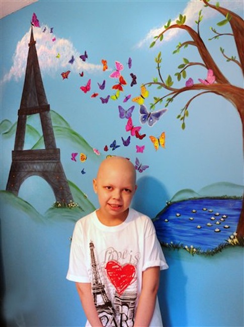 In this May 15, 2012 photo, Emma Jouneay, 9, poses in her bedroom by a mural that includes the Eiffel Tower in Merrimac, Mass. Jouneay, who was diagnosed with stage IV neuroblastoma, has collected souvenirs from 46 countries, 50 states and all the continents, through Emma's Pen Pal Adventure Around the World, born on Facebook in November. (AP Photo/Newburyport Daily News, Bryan Eaton)