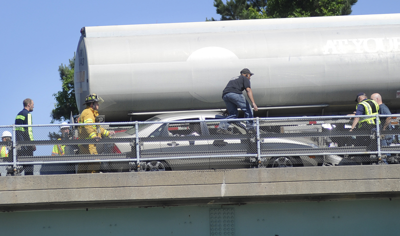 Crews work to remove a car wedged between a tractor-trailer and the guardrail on I-295 today.