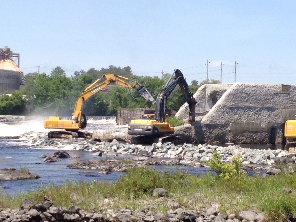 Machinery begins work today on the demolition of the cement fish ladder on the Great Works Dam.