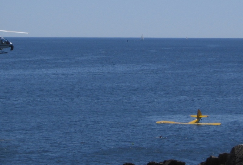 A witness to the plane crash took this photo shortly after the plane hit the water. The pilot can be seen in the water in front of the plane. The front of the helicopter that helped is visible at the far left.
