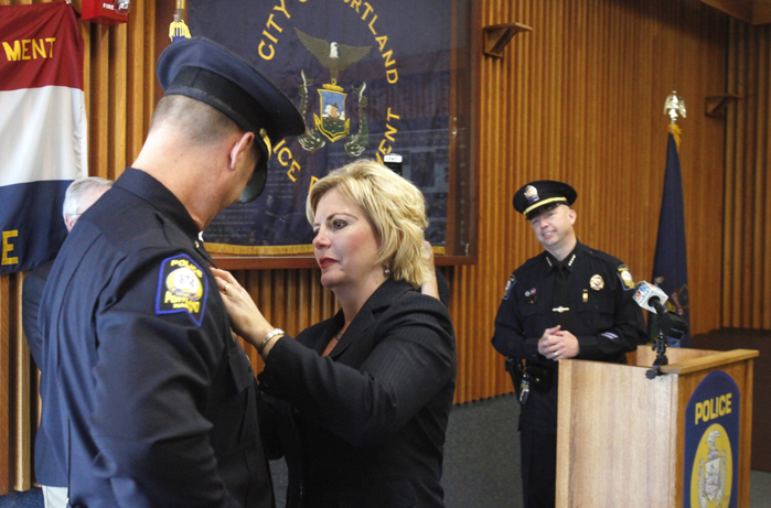 Cindy Rogers pins a badge on her husband Gary Rogers during a ceremony today at the Portland Police Department at which six officers were promoted. Rogers, who has 24 years of experience, was promoted to commander, the third highest ranking position at the department.
