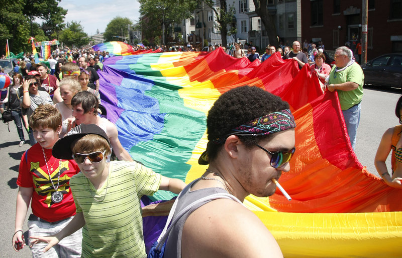 People of all ages join together to carry a 900-foot-long rainbow flag during the 2011 pride parade in Portland.
