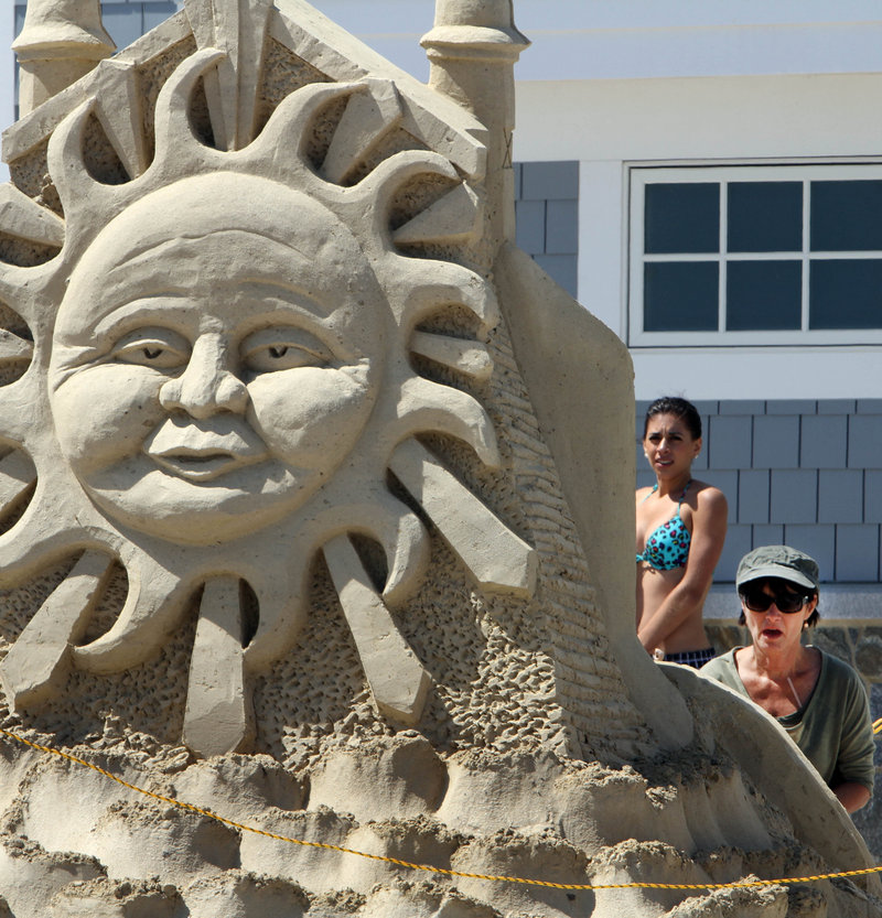 Darlene Grady Duggan puts the finishing touches on a sand sculpture Friday in front of the newly renovated Seashell entertainment complex and visitor center at Hampton Beach in Hampton, N.H.