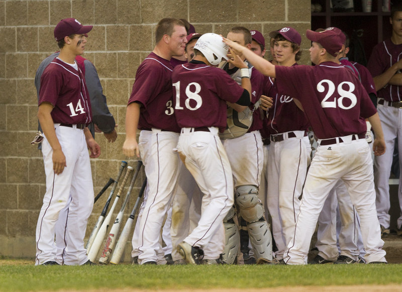 McGyver Poulin is greeted by his Windham teammates after scoring a run in the third inning against Cheverus.